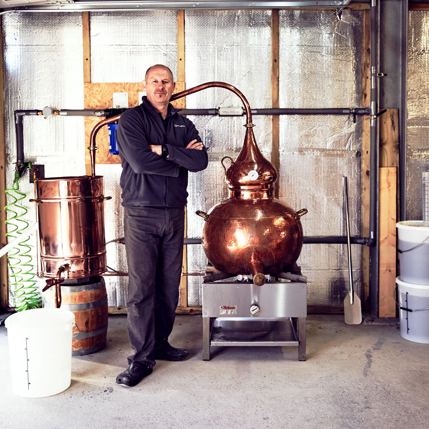 finlay geekie standing next to a copper still in gin distillery